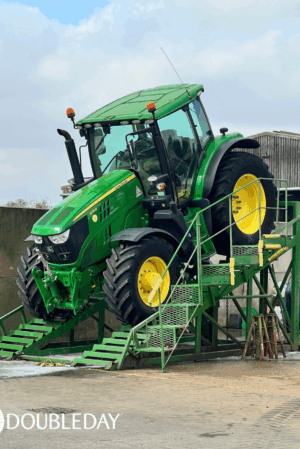 A John Deere 6155R tractor on a cleaning ramp being washed for export