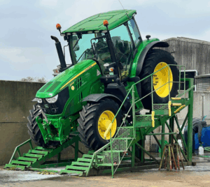 a John Deere 6155R tractor on a wash ramp, being cleaned for export